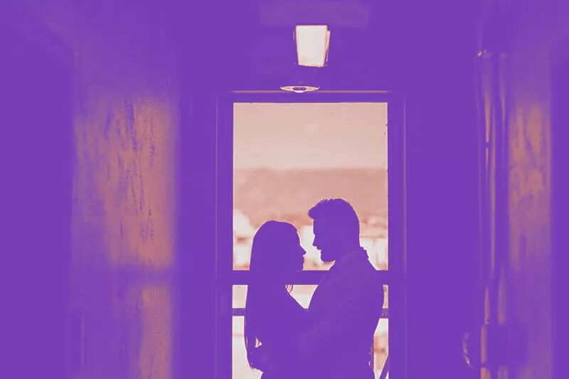 Couple standing in front of a door frame facing each other